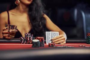 kvinna i elegant kläder sitter i cassino förbi tabell och spelar poker spel foto
