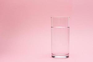 glas av vatten på en rosa bakgrund foto