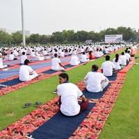 ny delhi, Indien, juni 21 2022 - grupp yoga övning session för människor på yamuna sporter komplex i delhi på internationell yoga dag, stor grupp av vuxna delta yoga klass i cricket stadion foto