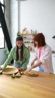 två flick skära frukt och skvaller i de kök foto