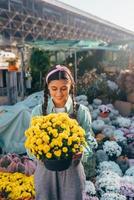 kvinna innehav dekorativ blomma i blomma pott på de marknadsföra. foto