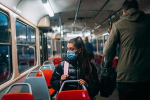 ung kvinna med mask reser i de offentlig transport. foto