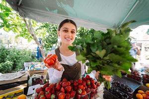 ung försäljare på arbete, innehav persilja och tomat i händer foto