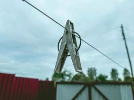 klädnypa hängande på en rep utomhus. torkning kläder efter tvättning på en sträng. trä- klädnypa med metall ringa foto