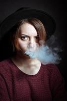 porträtt av en ung flicka i de rök av cigaretter foto