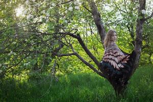 kvinna med befjädrad sjal Sammanträde i träd naturskön fotografi foto