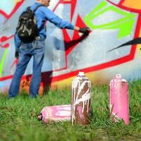 en få Begagnade måla burkar mot de bakgrund av de Plats med de vägg på som de ung kille drar en stor graffiti teckning. modern konst av teckning väggar i graffiti foto