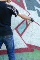 en ung ligist målarfärger graffiti på en betong vägg. olaglig vandalism begrepp. gata konst foto