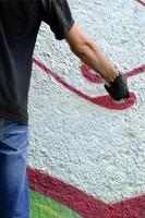 en ung ligist målarfärger graffiti på en betong vägg. olaglig vandalism begrepp. gata konst foto