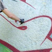 en hand i svart handskar målarfärger graffiti på en betong vägg. olaglig vandalism begrepp. gata konst foto