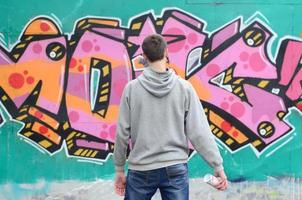 en ung graffiti konstnär i en grå luvtröja utseende på de vägg med foto
