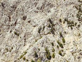 bergen i en varm, tropisk Land. textur med sand och stenar. bit av berg med grön buskar och örter. 3d bakgrund, naturlig textur foto