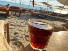 en glas med en mjuk dryck brun cocktail med soda och whisky på en tabell på de strand på de hav i en hotell på semester i en paradis värma östra tropisk Land tillflykt foto