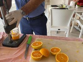 de bearbeta av framställning nyligen pressas gul orange juice, en man pressar juice in i en glas med hans händer i en hotell i en värma östra tropisk Land sydlig paradis tillflykt foto