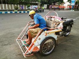 probolinggo, Indonesien. nov. 2022 - en riksha avdragare är väntar för passagerare i hans riksha på de sida av de väg i de eftermiddag foto