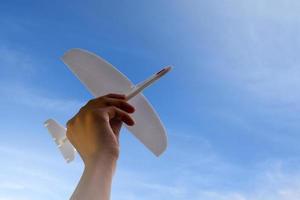 mini flygplan modell innehav i hand, blå himmel bakgrund, mjuk och selektiv fokus. foto