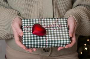 närbild av en kvinna innehav jul närvarande låda dekorerad med hjärta prydnad foto