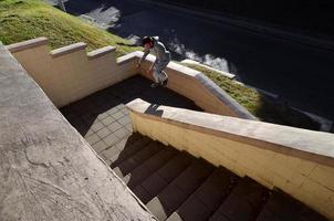 en ung kille utför en hoppa genom de Plats mellan de betong räcken. de idrottare praxis parkour, Träning i gata betingelser. de begrepp av sporter subkulturer bland ungdom foto