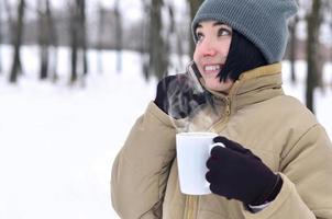 vinter- porträtt av ung flicka med smartphone och kaffe kopp foto