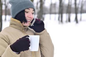 vinter- porträtt av ung flicka med smartphone och kaffe kopp foto