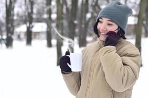 vinter- porträtt av ung flicka med smartphone och kaffe kopp foto