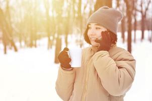 vinter- porträtt av ung flicka med smartphone och kaffe kopp foto