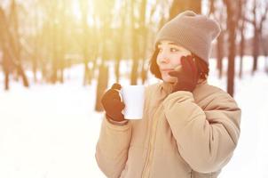 vinter- porträtt av ung flicka med smartphone och kaffe kopp foto