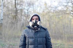 porträtt av ung man i skyddande gas mask utomhus i vår trä foto