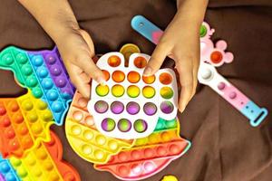 pop- den är en flerfärgad anti-stress leksak i barns händer. bubbla spel. antistress leksaker. foto