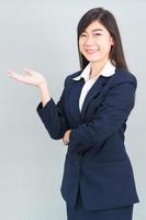asiatisk kvinna i kostym öppen hand handflatan gester med tömma Plats foto