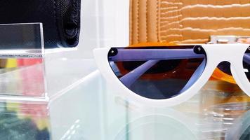 stänga upp vit solglasögon på glas tabell eller hylla med suddig brun läder väska bakgrund för försäljning på mode Lagra eller affär. sommar Tillbehör och objekt skydda ögon från solljus eller uv ljus foto
