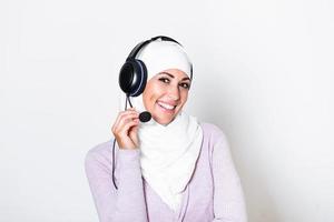 ung muslim kvinna med hijab scarf kund representativ företag kvinna med telefon headsetet portion och stödjande uppkopplad med kund i modern ring upp Centrum foto
