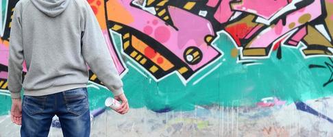 en ung graffiti konstnär i en grå luvtröja utseende på de vägg med foto