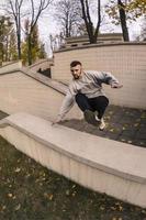 en ung kille utför en hoppa genom de betong parapet. de idrottare praxis parkour, Träning i gata betingelser. de begrepp av sporter subkulturer bland ungdom foto