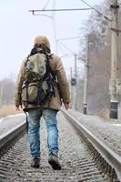 en man med en stor ryggsäck går ett huvud på de järnväg Spår duri foto