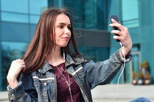 ung flicka håller på med selfie på de bakgrund av ett kontor byggnad foto