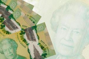 20 kanadensisk dollar räkningar lögner i stack på bakgrund av stor halvtransparent sedel. abstrakt företag bakgrund foto