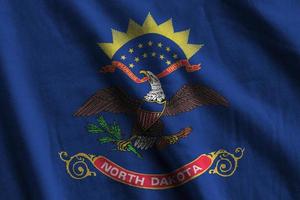 norr dakota oss stat flagga med stor veck vinka stänga upp under de studio ljus inomhus. de officiell symboler och färger i baner foto