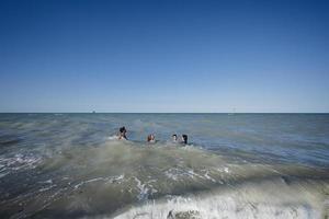 familj med barn simning i adriatisk hav på strand porto sant elpidio, Italien. foto