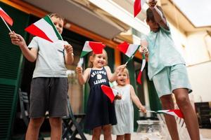 Lycklig fyra barn med italiensk flaggor fira republik dag av Italien. foto