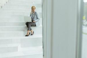 affärskvinna använder sig av mobil telefon på modern kontor trappa foto