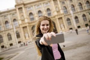 ung kvinnlig turist som tar selfie med mobilfoto i mitten av wien, österrike foto