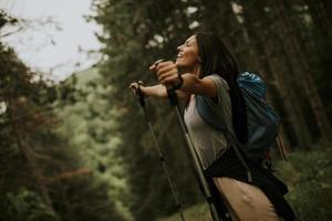 ung kvinna backpacker kvinna njuter grön skön skog runt om henne foto