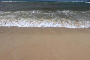 hav Strand med sandig strand och framåt Vinka. vatten skum med slät sand. skön vågor på de sand strand bakgrund. foto