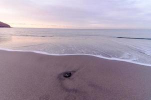 strand och våg vid soluppgången foto