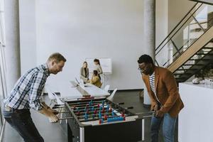 ung tillfällig multietnisk företag människor spelar tabell fotboll och avkopplande på kontor foto