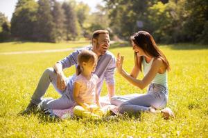 lycklig ung familj med söt liten dotter som har kul i parken på en solig dag foto