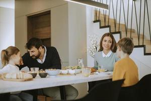 ung Lycklig familj talande medan har frukost på dining tabell foto