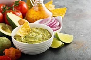 guacamole i vit skål med kalk och varm peppar foto