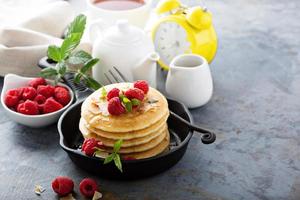 stack av fluffig kärnmjölk pannkakor med hallon och kokos foto